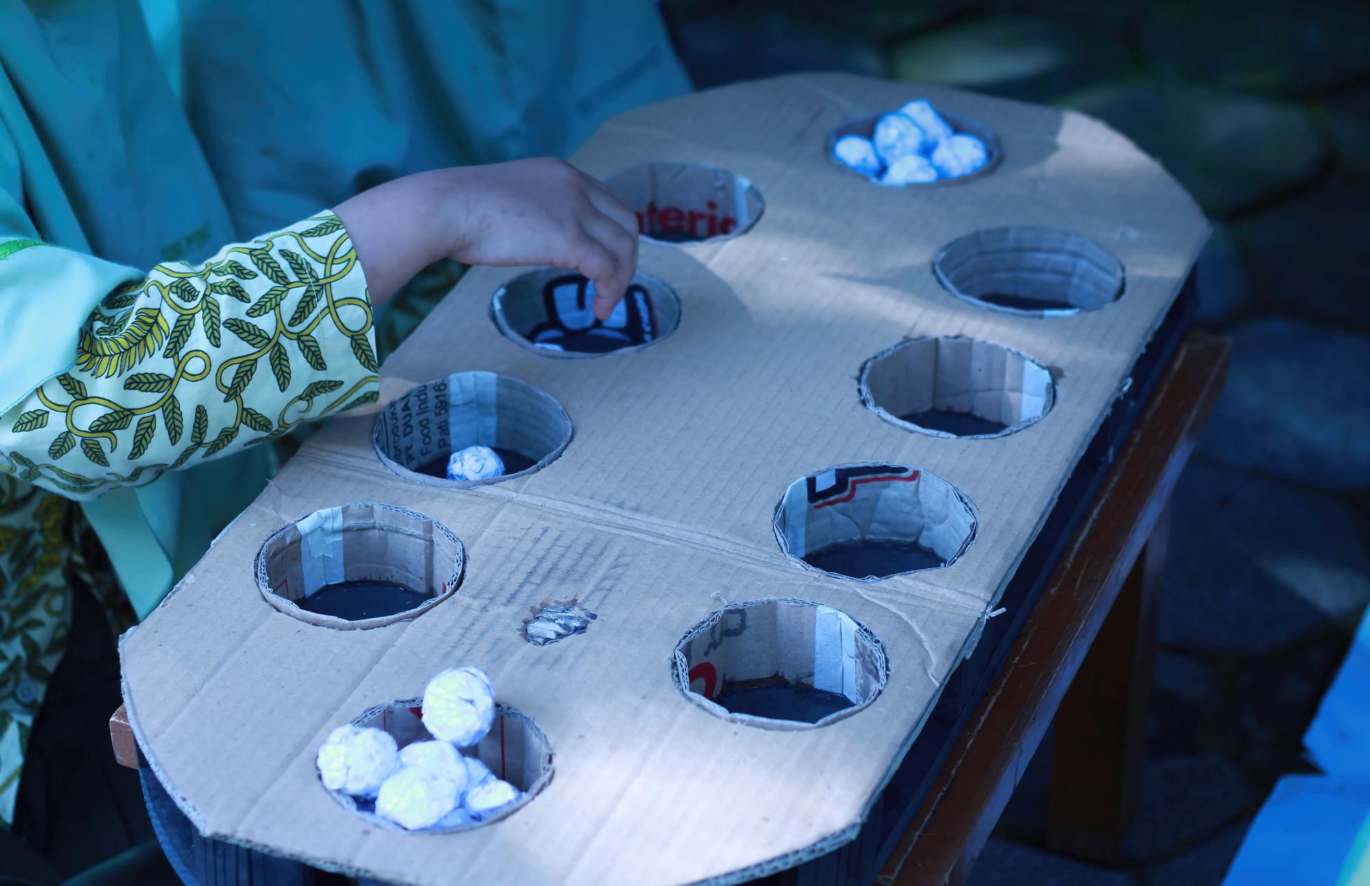 child-playing-dakon-with-recycled-materials-traditional-indonesian-game-close-up_824200-23